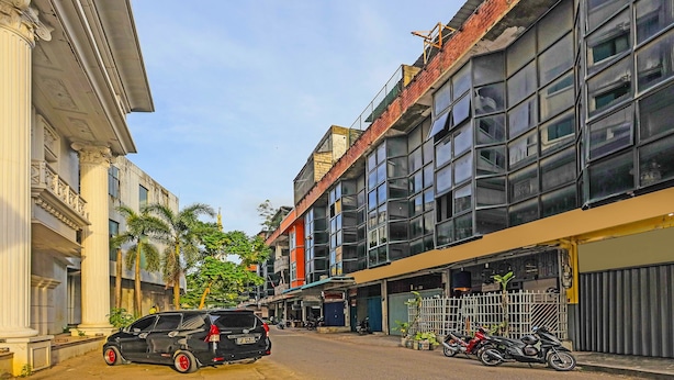 A street view with a black SUV parked on the side, buildings with large windows, and a few motorcycles parked in front of a shop. - Hotel O Penginapan ReniNearMall Nagoya Hill (Batam)