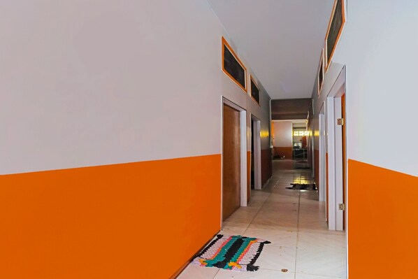 A hallway with orange and white walls, doors, and a patterned rug on the floor.