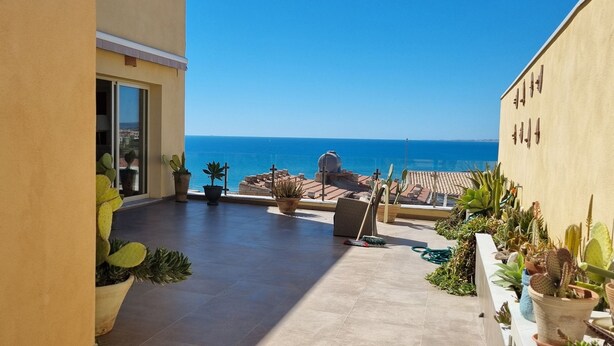 A balcony with potted plants, a view of the sea, and a tiled floor. - Apartment with the most beautiful sunset in Sicily (Frazione Cava d'Aliga, Scicli)