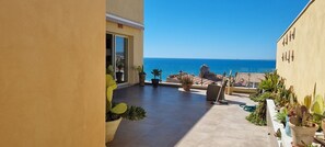 Un balcon agrémenté de plantes en pot, une vue sur la mer et un sol carrelé.