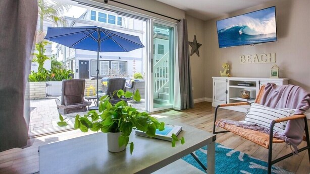 A living room with a large window, a blue umbrella, a beach-themed TV, and a star decoration.