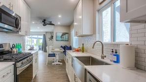 A modern kitchen with white cabinetry, stainless steel appliances, and a large window providing natural light.