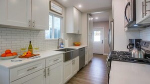 A modern kitchen with white cabinets, a stainless steel sink, and a gas stove.