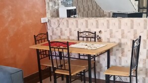 Ein Essbereich mit Tisch und Stühlen, einer Couch und einer Treppe im Hintergrund.