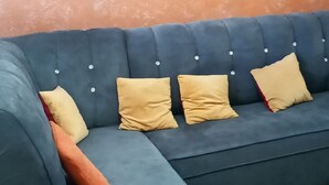 Ein modulares Sofa mit vielen Kissen, ein gerahmtes Kunstwerk an der Wand und ein gemustertes Teppich.