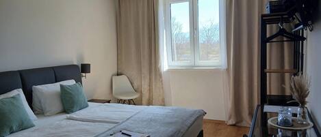 A neatly arranged bedroom with a bed, bedside tables, a chair, and a window with curtains.
