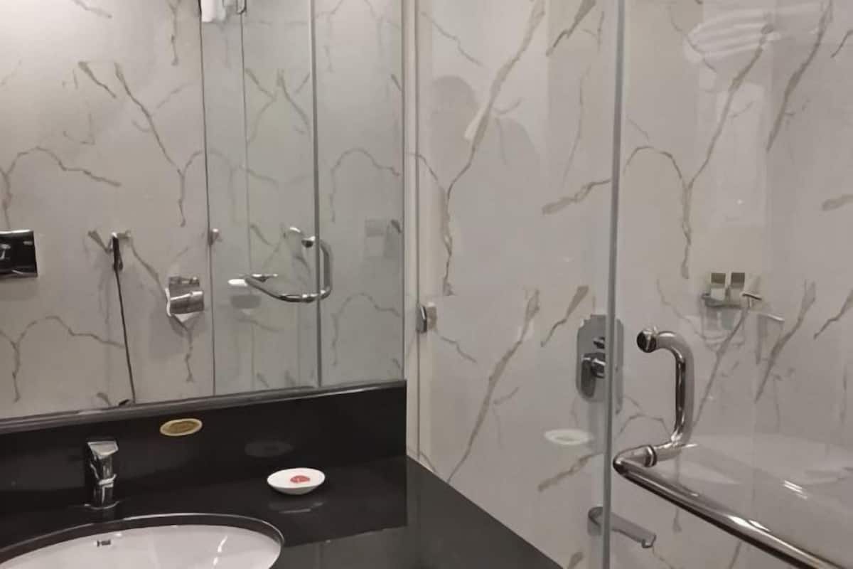 A bathroom with a marble wall, a sink, and a mirror.