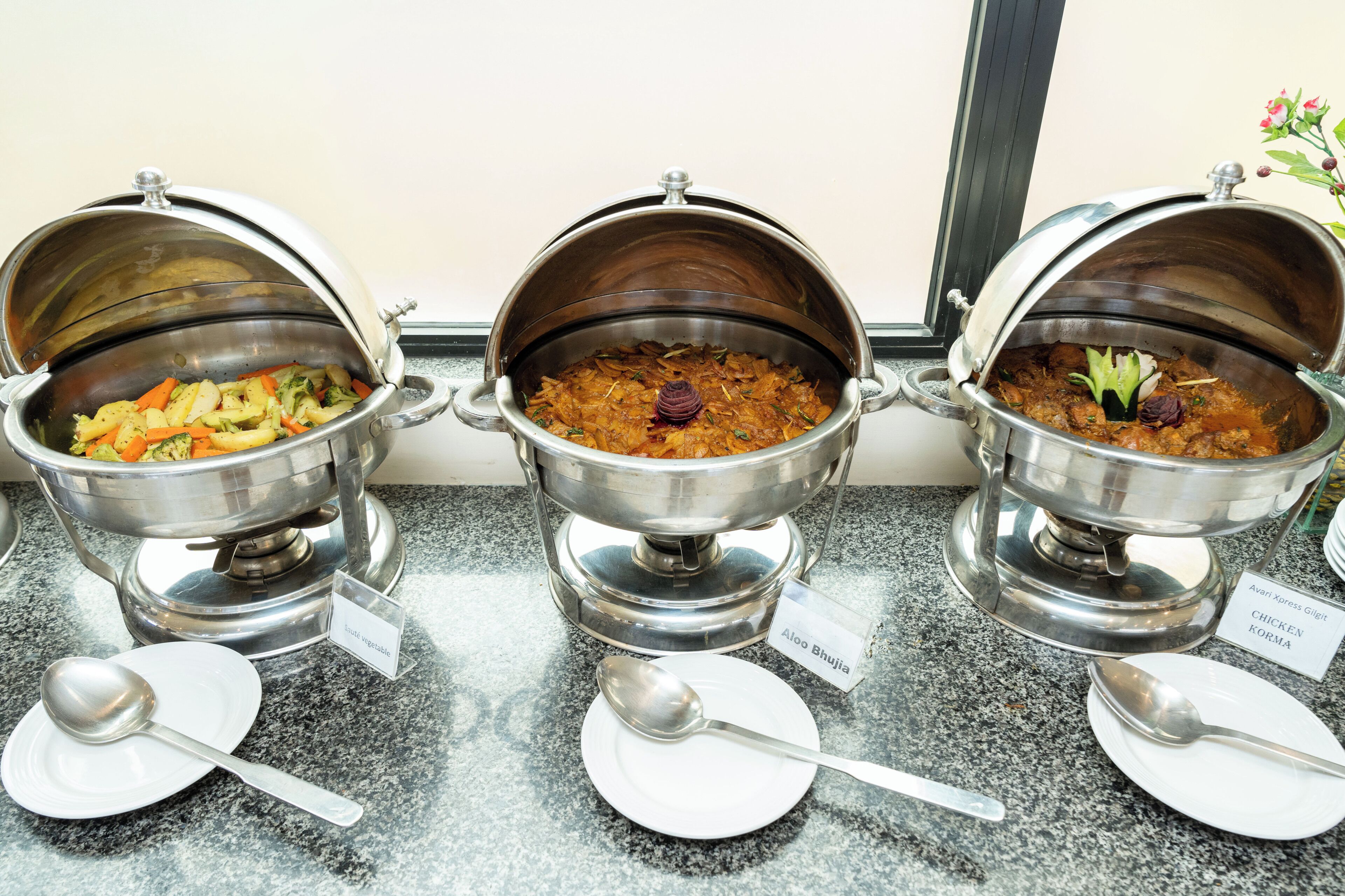 Tres dispensadores de acero inoxidable para alimentos con etiquetas sobre una encimera.