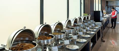 A buffet line with various food options, including French toast and paratha, in a modern hotel setting.