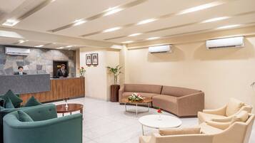 Un vestíbulo de hotel con mostrador de recepción, zona de estar y unidades de aire acondicionado.