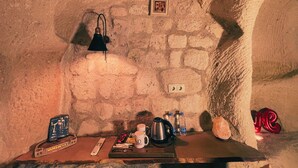 Une pièce aux murs de pierre, avec une table sur laquelle se trouvent une télécommande, une tasse, une bouilloire et une bouteille d’eau.