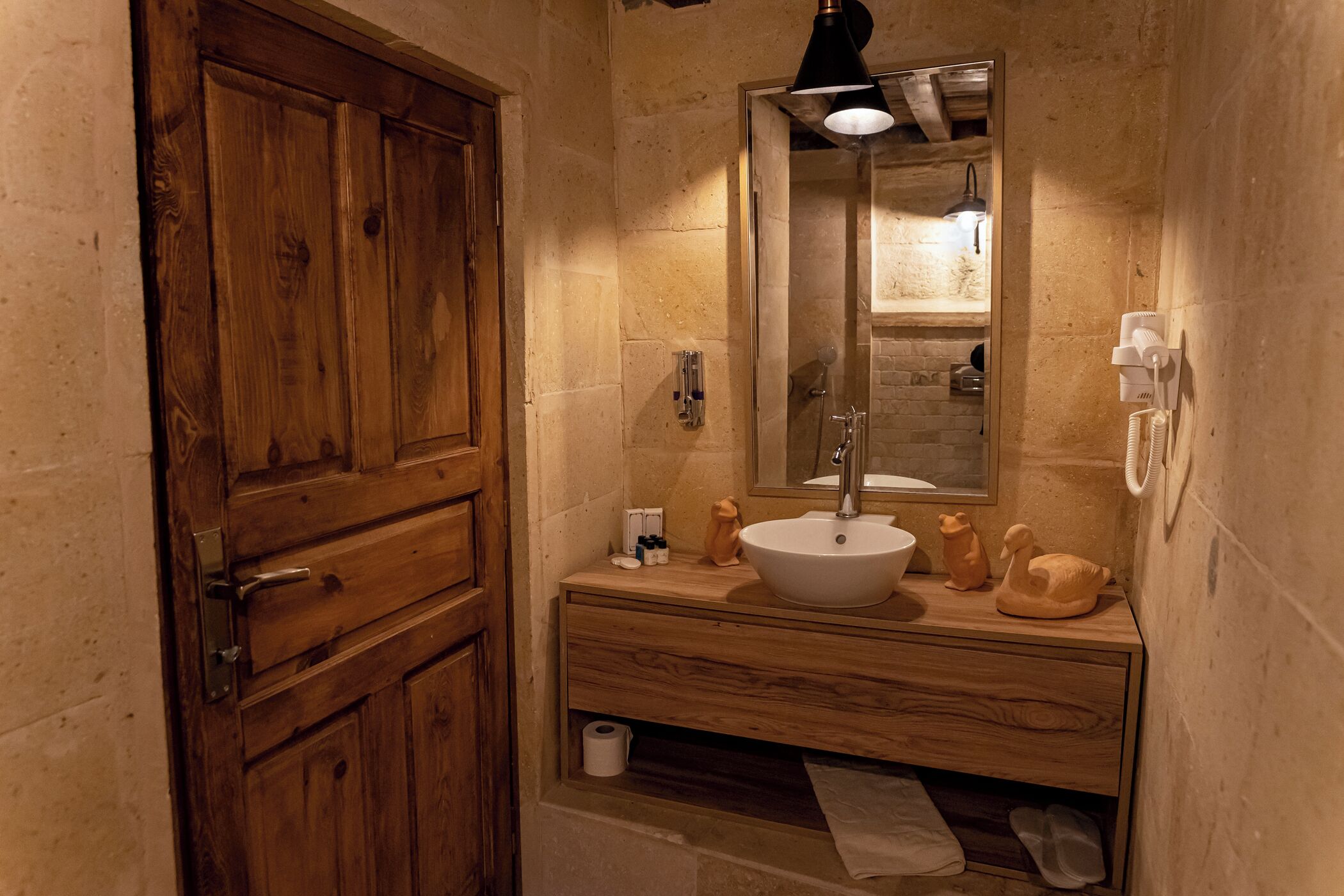 A wooden cabinet with a mirror, a sink, and decorative items on a wooden vanity.