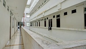 Un long couloir, doté de nombreuses portes et fenêtres, qui mène à différentes pièces.