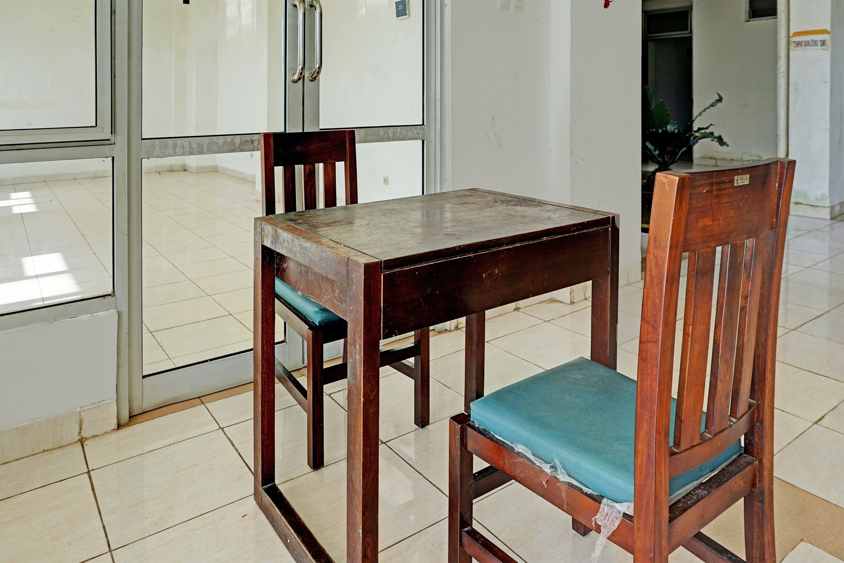 A wooden table and chairs in a room with tiled flooring and white walls.