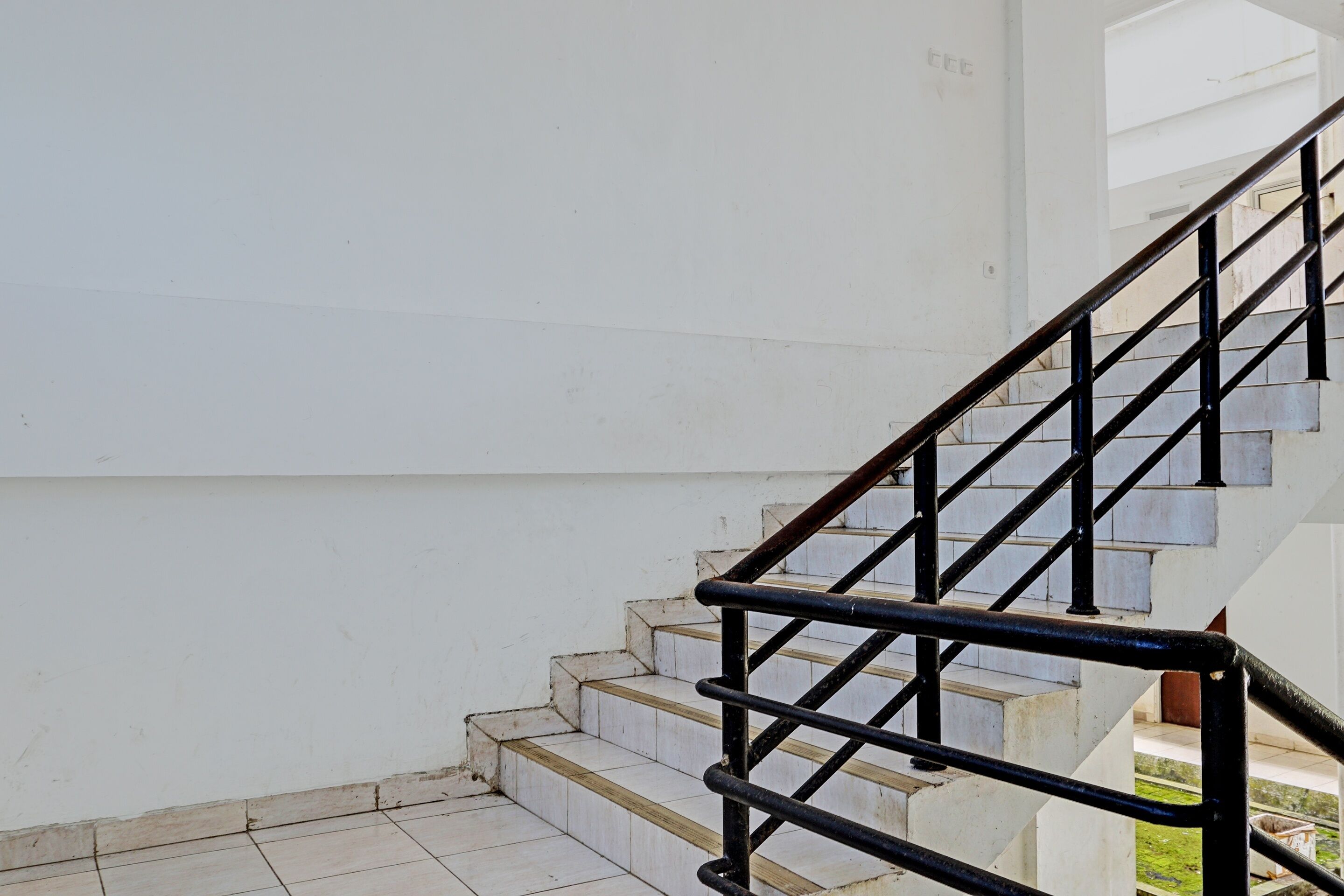 A staircase with black railings and white steps, leading to an upper level.