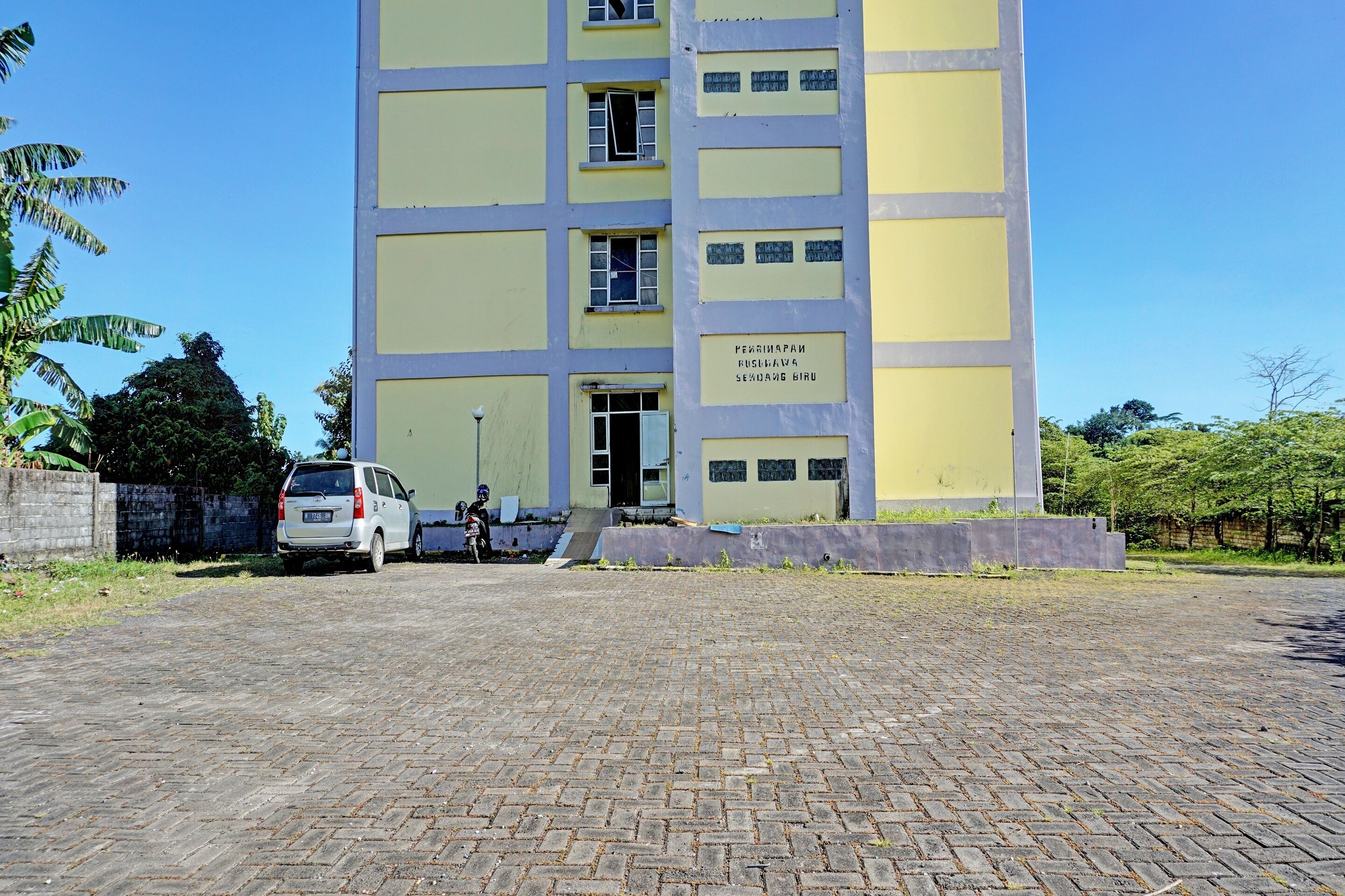 A multi-story building with a yellow facade and a sign indicating it is a dormitory.