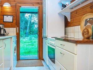 A kitchen with a view of a green landscape through a door. - 6 Person Holiday Home in Henne (Henne)