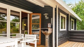 A wooden deck with a white table and chairs, a metal outdoor sink, and a window overlooking greenery. - 6 Person Holiday Home in Henne (Henne)