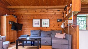 A cozy cabin interior with a sofa, a coffee table, a TV, and a bookshelf. - 6 Person Holiday Home in Henne (Henne)