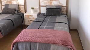 A room with two beds, a small bedside table with a plant, and a decorative headboard. - HARMONIA Apartment with Spectacular Ocean View (Portocolom)
