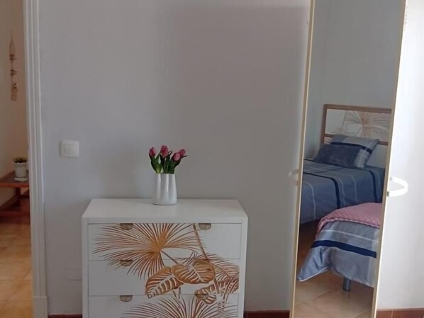 A bedroom with a bed, a bedside table with a vase of flowers, and a decorative cabinet with leaf patterns.
