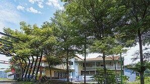 A building with multiple floors, a balcony, and a paved area with trees. - OYO Flagship 90886 Sunset View Homestay (Mojokerto)