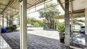 A covered outdoor area with stone paving, potted plants, and a view of a street with vehicles. - OYO Flagship 90886 Sunset View Homestay (Mojokerto)
