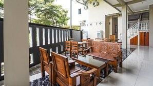A dining area with wooden furniture and a glass table, a staircase, and a view of trees outside. - OYO Flagship 90886 Sunset View Homestay (Mojokerto)