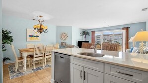 Een moderne keuken met grijze kastjes, een centraal eiland en een eethoek met een houten tafel en stoelen.