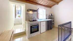 A modern kitchen with a built-in oven, a stove, and a sink. There is a window providing natural light and a view of the outside. - Solemar Sicilia - Monacò Rooms (Palermo)