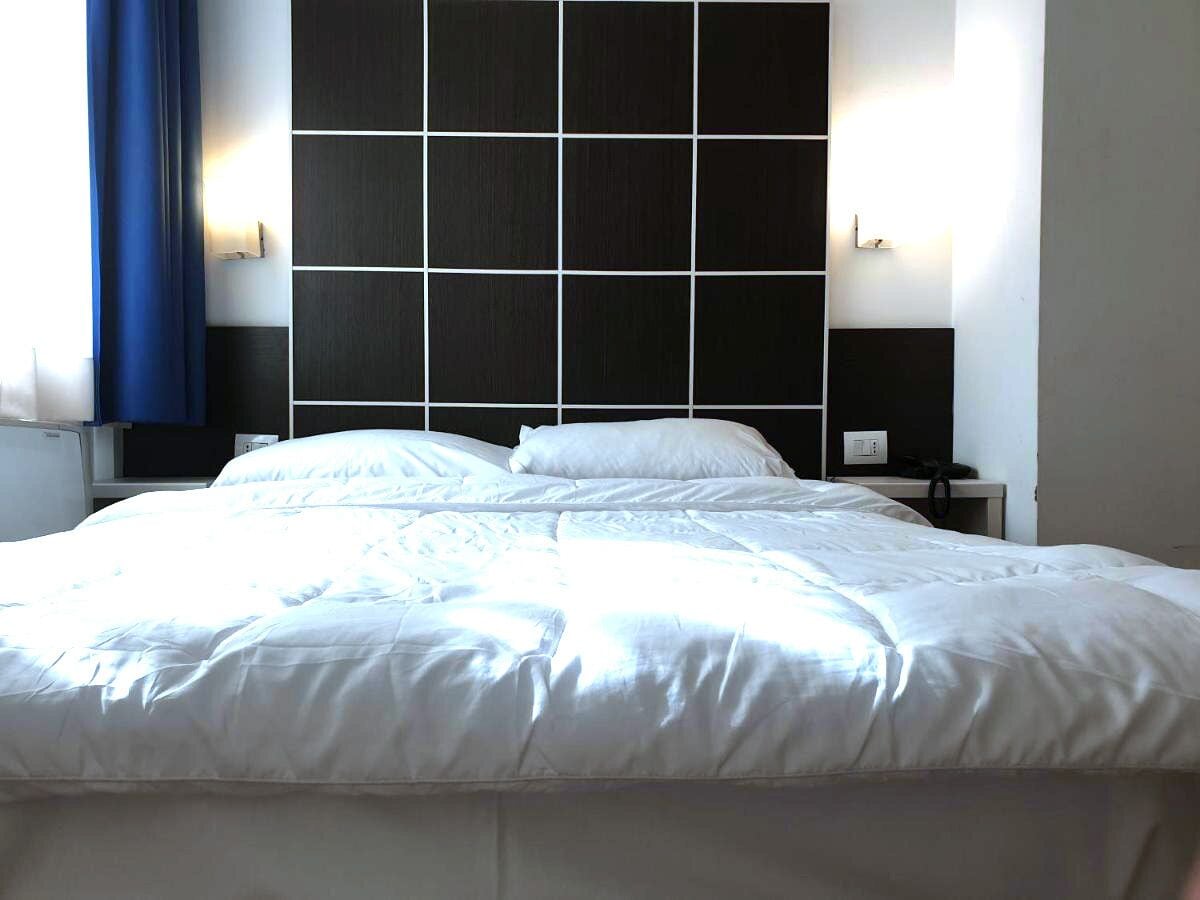 Una cama bien hecha en una habitación de hotel con un cabecero moderno y mesitas de noche.