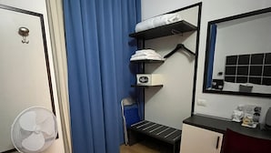 A compact room with a bed, a desk, a chair, a small table, a fan, and a mirror. - Hotel Vitruvio (Milan)