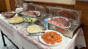 A buffet table with various food items including eggs, pasta, sliced tomatoes, and deli meats. - Hotel Vitruvio (Milan)