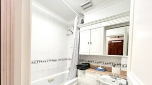 Un baño con bañera, inodoro, lavabo y un espejo sobre el lavabo.