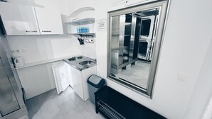 Een kleine keuken met een spoelbak, fornuis en spiegel.