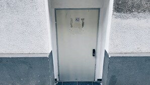 A white door with a sign reading "A2" above it, set in a white wall with a textured surface.