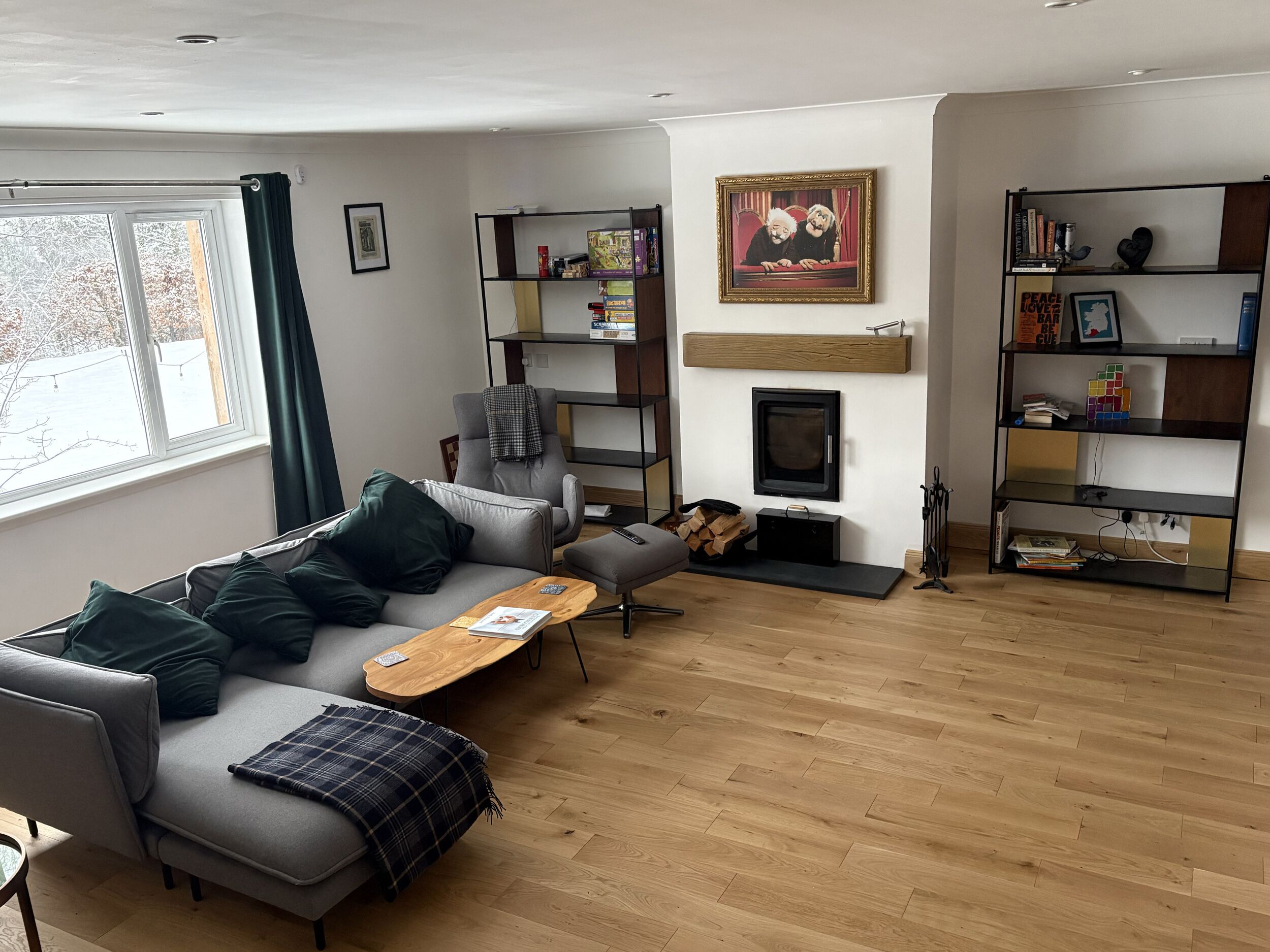 Un salon moderne avec un canapé gris, une table basse en bois, une cheminée et des étagères intégrées.