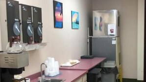 A kitchen with a pink countertop, a coffee machine, a sink, and a refrigerator.
