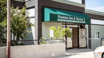 The exterior of Manistee Inn & Marina with a green awning, a sign indicating 'Motel Parking Only', and a flag outside the entrance.