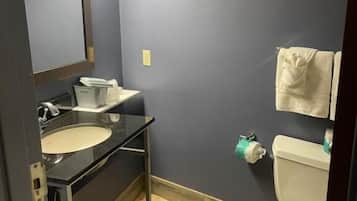 Et badeværelse med vask, spejl og toilet.