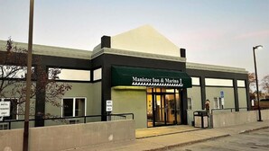 The exterior of Manistee Inn & Marina with a green awning, a parking sign, and a handicap-accessible entrance.