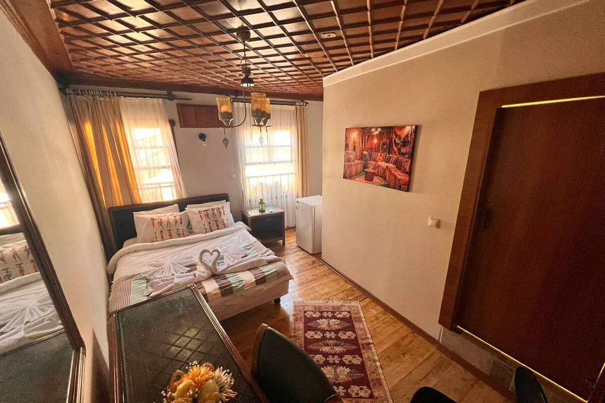 Ein Schlafzimmer mit einem Bett, einem Schreibtisch mit Stuhl, einem Teppich und einem Bild an der Wand.