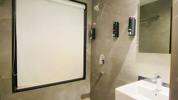 Une salle de bain moderne avec un grand miroir, un lavabo et une douche.