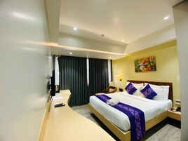 Una habitación de hotel con una cama, mesitas de noche, un escritorio y un cuadro en la pared.