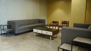 Uma sala de estar com um sofá cinzento, duas poltronas, uma mesa de centro e uma mesa lateral.