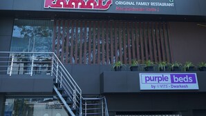 Um edifício de vários andares com um restaurante chamado 'Kopats' no andar térreo, apresentando uma fachada moderna com ripas verticais e grandes janelas.
