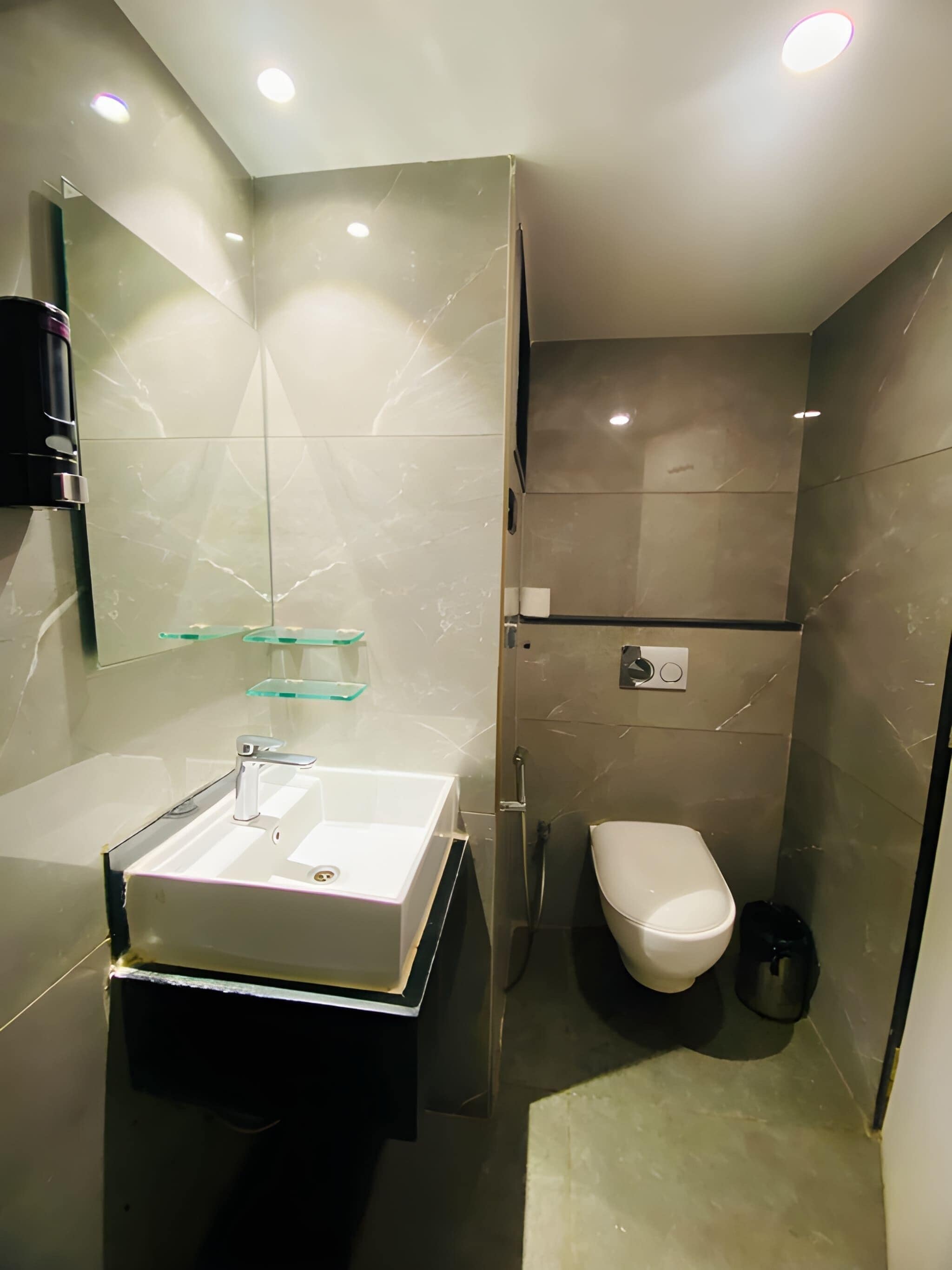Un bagno moderno con mobile lavabo, lavandino, specchio e water.