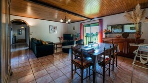 Un salon chaleureux avec un plafond en bois, un coin repas avec une table et des chaises, et un téléviseur.