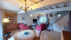 A spacious living area with a high ceiling, a chandelier, a television, and a staircase. - Gîte l'Ostalet de Sarron avec piscine, Brax - Lot et Garonne (BRAX)