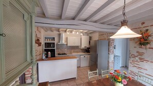 A kitchen with white cabinets, a wooden island, and a hanging light fixture. - Gîte l'Ostalet de Sarron avec piscine, Brax - Lot et Garonne (BRAX)